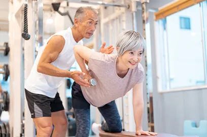 フィットネスジムで鍛えている老夫婦の画像